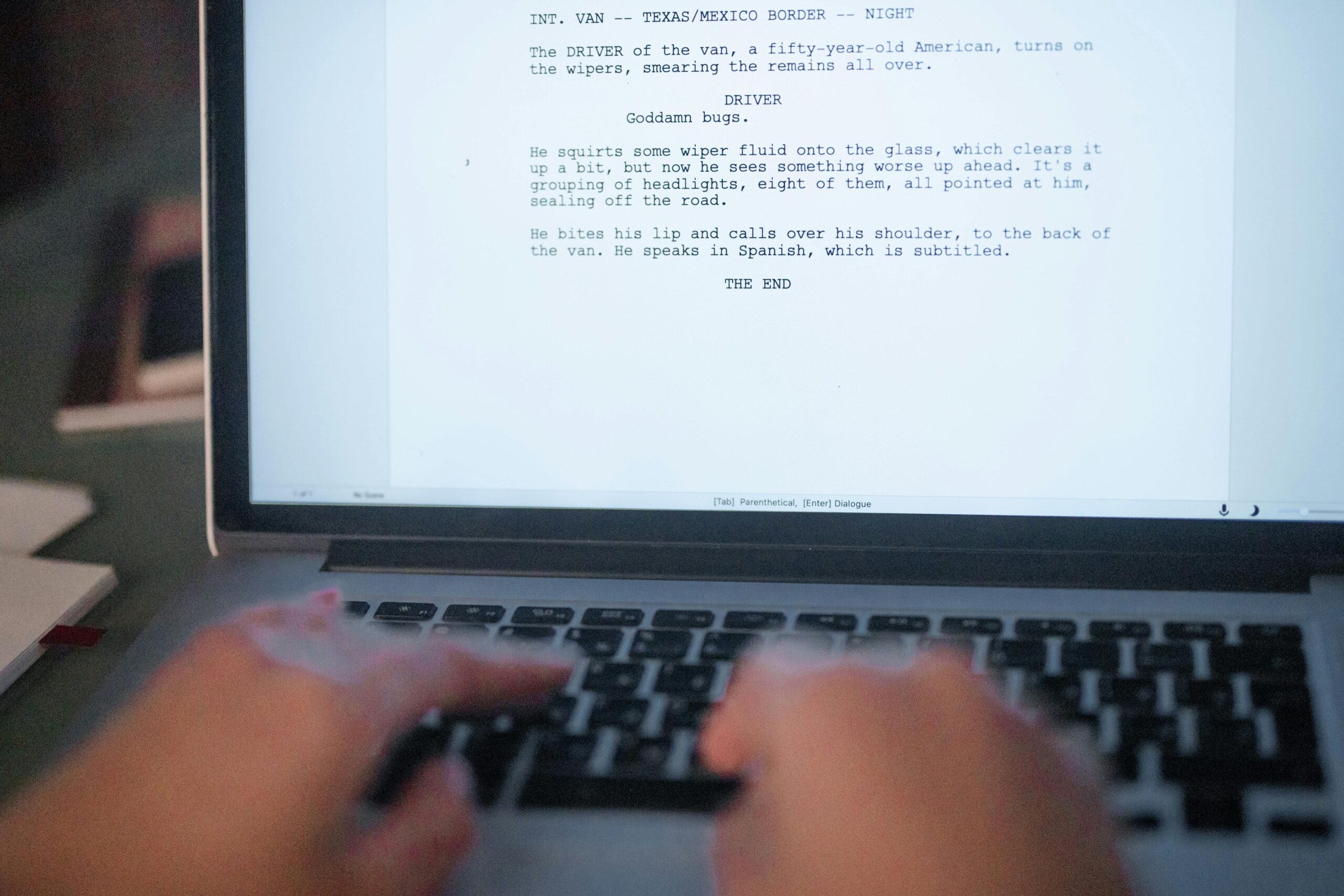 A close-up shot of hands typing a film script on a laptop, focusing on creativity and screenplay writing.